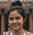 A girl with her hair in a bun, smiling and posing for a picture outdoors.