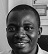 A black and white photo of a smiling man looking directly at the camera.